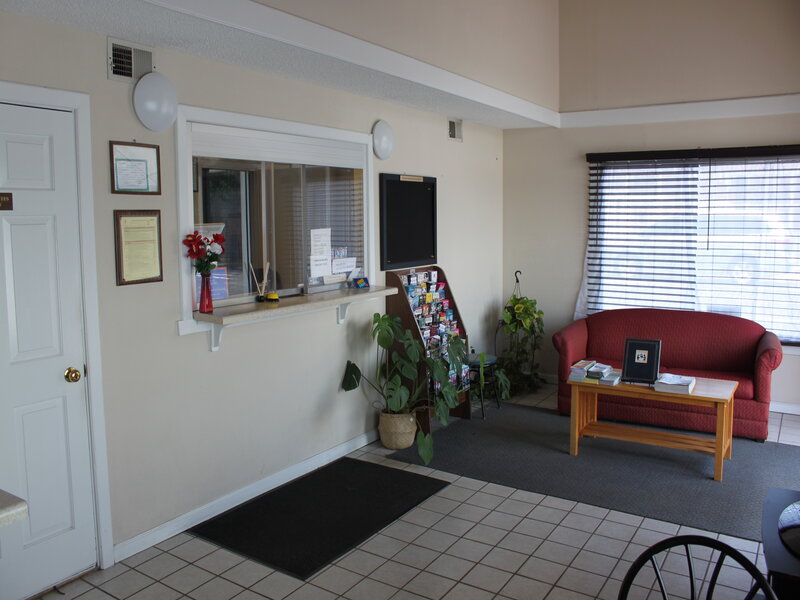Welcoming lobby with red sofa, reception window, and seating area at Travel Inn of Buford