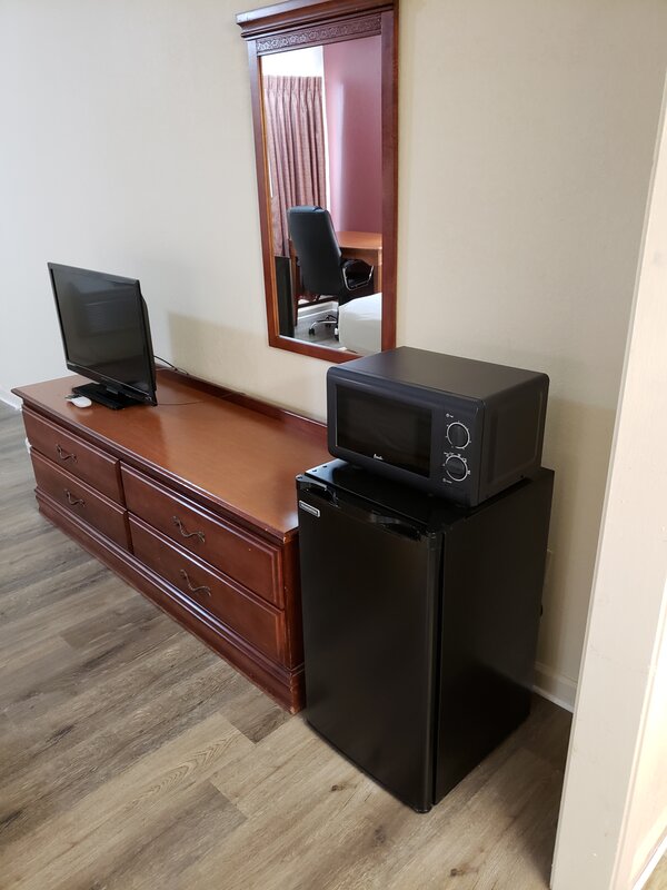 Wooden dresser with flat-screen TV, mini-fridge and microwave in guest room at Travel Inn of Buford