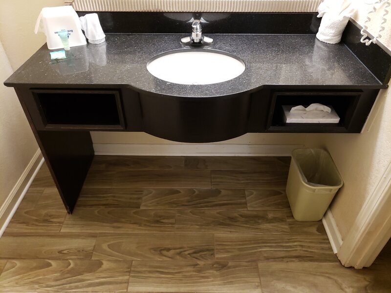 Wall-mounted vanity with dark granite countertop and storage cubby at Travel Inn of Buford