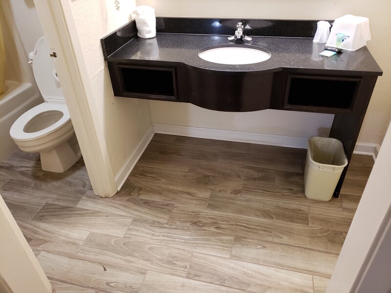Modern bathroom vanity with dark countertop and wood-style flooring at Travel Inn of Buford