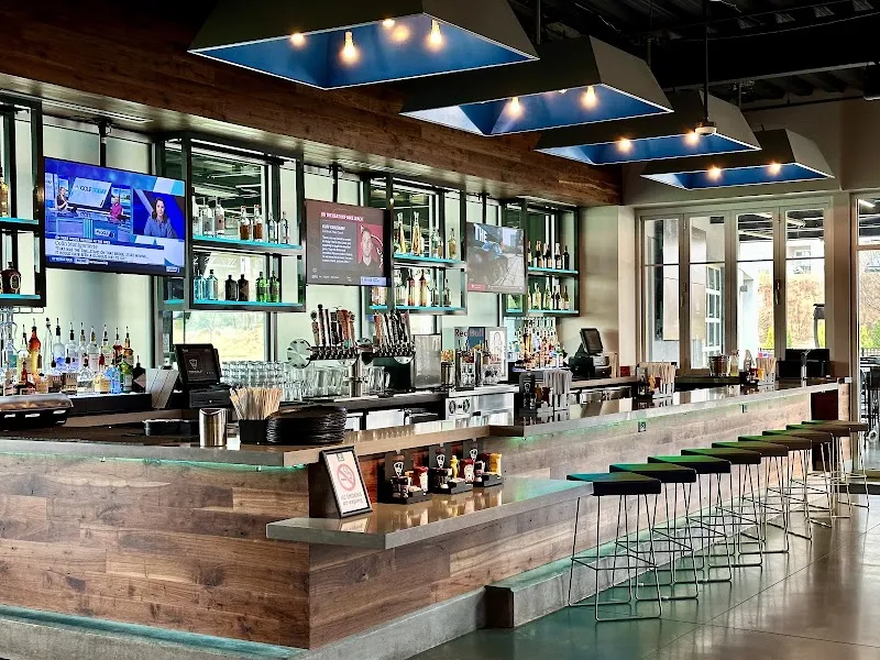 Modern bar area at Topgolf Buford with wooden counter and blue ceiling panels
